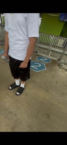 Customer wearing the white Mystery Socks with black sandals and shorts while standing.