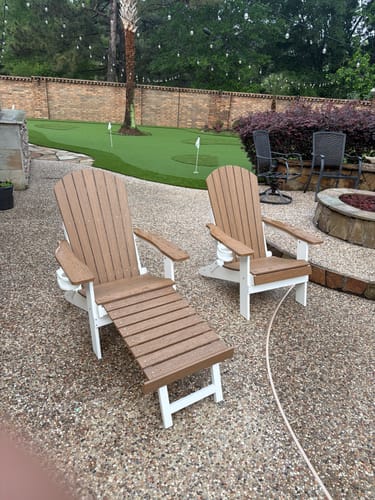 Customer's two two-tone Folding Adirondack Chairs on a patio. One chair has its built-in footrest extended.