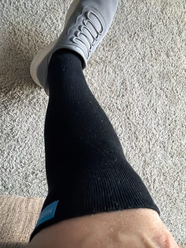 A customer's lower leg and foot, wearing a black Performance Eucalyptus Compression Sock and a grey shoe.