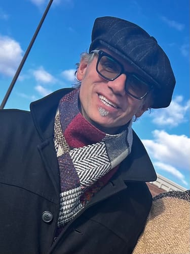 Close-up of a customer smiling while wearing the striped Shelby Baker Boy Eight Piece Cap.