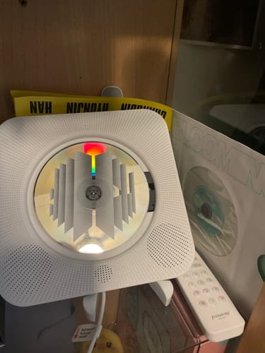 Customer's white ASTRONORD™ CD Player on a shelf with a decorative CD inside, placed next to K-pop merchandise.