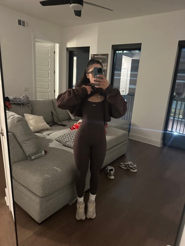 Reviewer's mirror selfie showing the full-length fit of the Espresso Onesie with a cropped jacket.