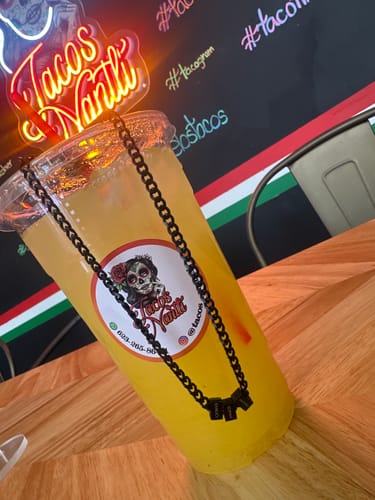 Customer's black Legacy necklace displayed over a drink cup on a wooden table.