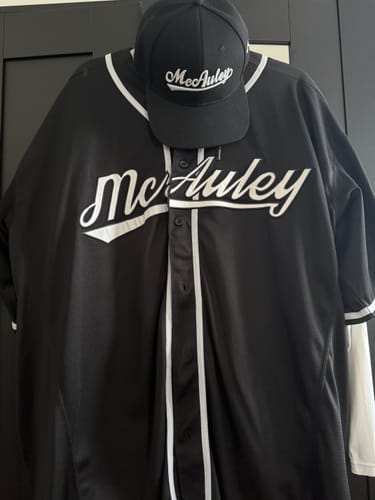Customer's custom black baseball cap with 'McAuley' embroidery, shown with a matching baseball jersey.