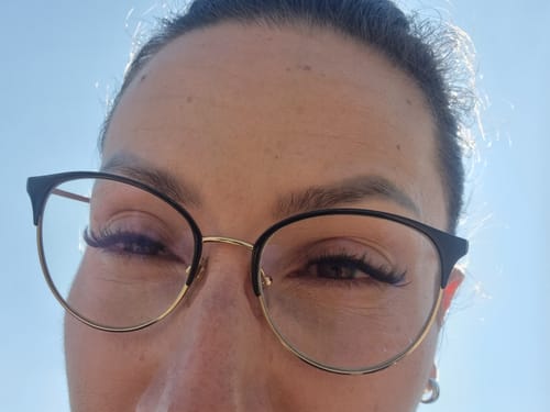 Nahaufnahme einer Kundin mit Brille, die ihre voluminösen Flaw Lash Wimpern zeigt.