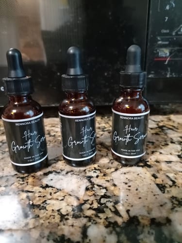 Customer's three bottles of Rennora Hair Growth Serum sitting on a granite countertop.