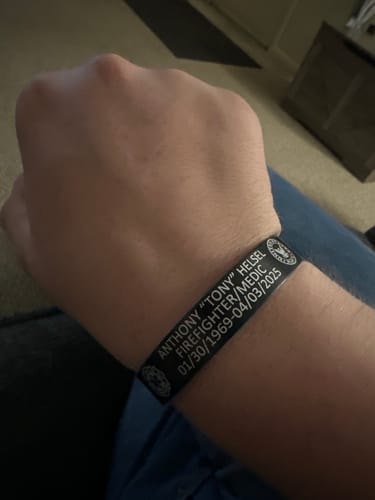 Close-up of a reviewer wearing their custom black bracelet with personalized engraving.