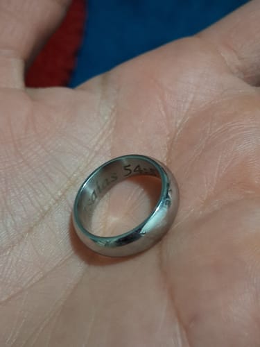 A reviewer holds the stainless steel 6mm Dome Wedding Band in their palm, showing the inner engraving.