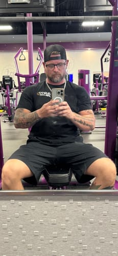 Reviewer in a black NEVER GIVE UP TEE taking a mirror selfie at the gym.