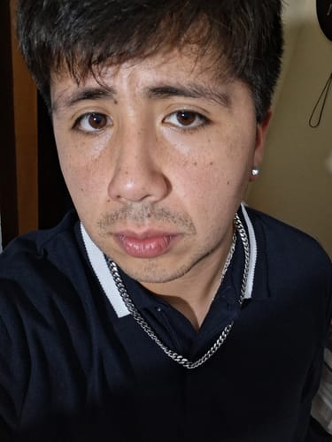 Primer plano de un cliente luciendo la Cadena Cuban Link de 8mm sobre un polo oscuro.