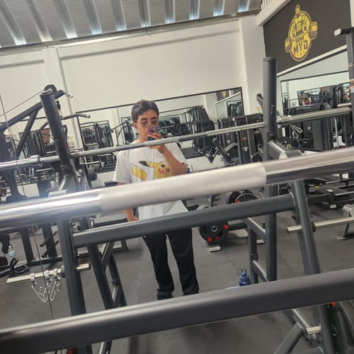 Cliente usando la camiseta blanca Yellow Strike 025 en un selfie en el espejo del gimnasio.