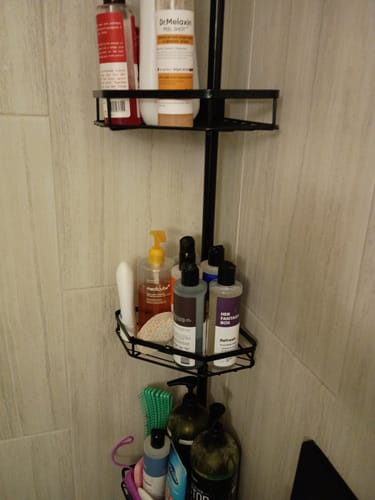 Reviewer's Refresh Yoni Gel Wash on a black shower caddy filled with various personal care items.