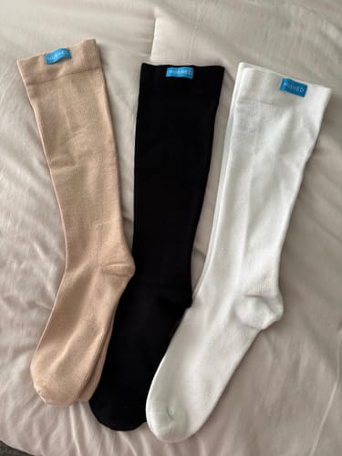 Customer's three pairs of Performance Eucalyptus Compression Socks laid out in beige, black, and white.
