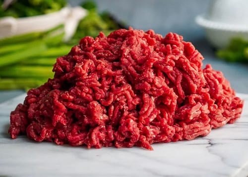 Customer's fresh red mound of Grass-fed Grass-finished Ground Beef on a marble surface.