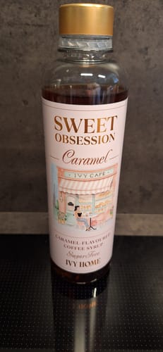 Reviewer's bottle of Sweet Obsession Caramel Coffee Syrup, showing the sugar-free version with its pink label and gold cap.
