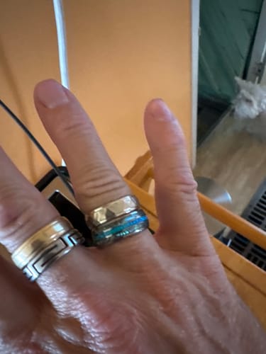 A customer's hand wearing the shiny Vanguard ring, showing its silver band and colorful inlay.