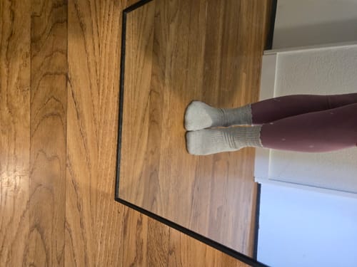 Customer's feet wearing the grey Dual-Direction Grip Basics socks on a wood floor.