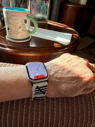 Reviewer wearing a smartwatch with a white and black tally-mark-design band on their wrist.