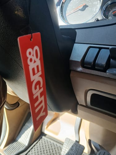 Customer's red 80Eighty air freshener hanging from the steering column inside a car.
