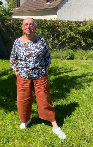 Cliente portant le Pantalon Briac en lin terracotta dans son jardin.