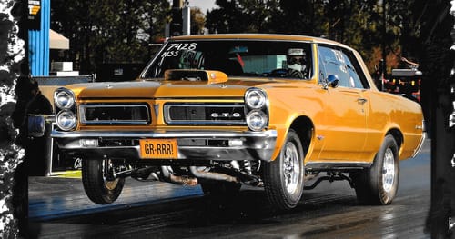 Reviewer's gold '65 GTO drag car lifting its front wheels off the ground on a track.