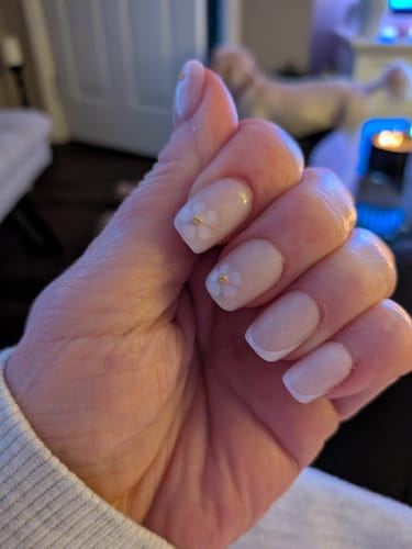 Reviewer's hand showing the short, square In Bloom press-on nails with a delicate flower design after one week of wear.