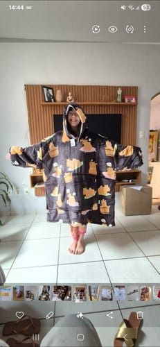 Cliente usa o cobertor vestível Sleepo Pug oversized, mostrando seu tamanho grande em casa.