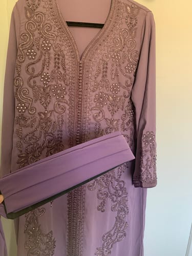 Customer holding the matching belt in front of their purple Kaftan Larimar, showing its intricate embroidery.