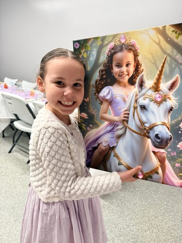 Customer smiling, holding a large canvas of 'The Lavender Unicorn Princess' that depicts her as a princess on a unicorn.