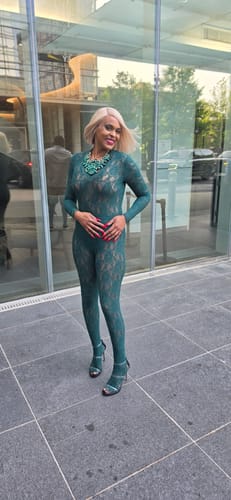Reviewer standing outdoors in the green, long-sleeved Stretch Lace Bodysuit, styled as a full outfit.