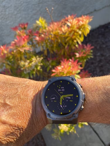 A customer wearing the Gard Pro Ultra 3 watch on their wrist outdoors, showing its dark gray case and black and yellow display.