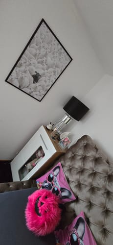 Customer's 'The Black Sheep' art print in a black frame, hanging on a white wall in a bedroom.