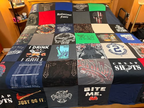 Customer's large Project Repat T-Shirt Quilt, a keepsake made from many t-shirts, spread neatly across a bed.