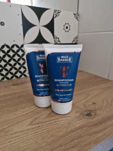 Client montrant deux tubes bleus du Shampoing Anti Chute Homme sur un comptoir en bois.