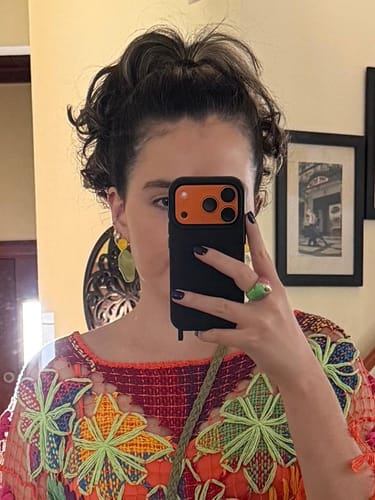 Cliente tirando uma selfie no espelho com seu celular, mostrando a Case Pretop com detalhe laranja na câmera.