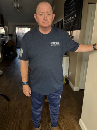 Reviewer standing indoors wearing the front of the dark Lowered in Honor t-shirt.
