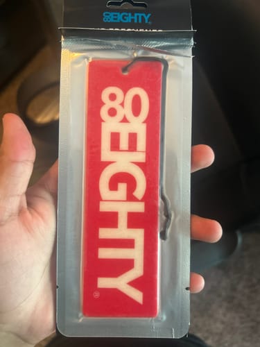 Reviewer holding a red 80Eighty Smoke Ice Air Freshener in its original clear packaging.
