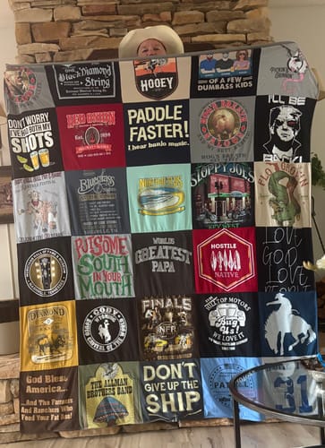 Customer holding up a large T-Shirt Quilt made of colorful shirt panels.