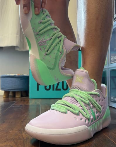 Customer wearing one pastel green and purple Joker 2 'Inspire' shoe while holding up the matching shoe to show the design.