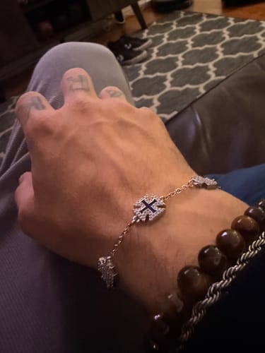 Cliente usando la Pulsera Legacy en su muñeca, mostrando las cruces de cristal y la cadena fina.