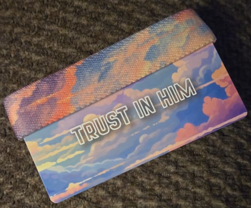 Customer's Trust In Him bracelet and its packaging card, which both feature a colorful cloudscape design.