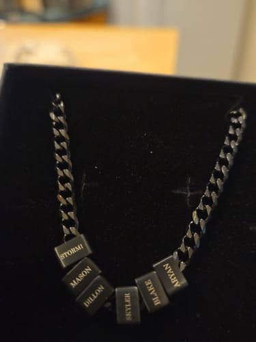 Reviewer's Legacy necklace with six engraved name beads on a dark chain, resting in its presentation box.