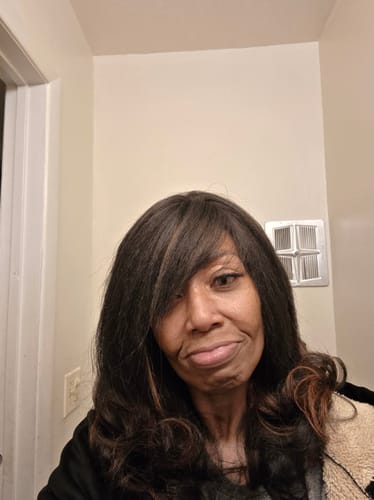 Reviewer's selfie showing the long, textured Outre Kinky Soft Edges Wig styled with a side-swept bang.