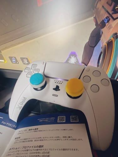 レビューワーの白いコントローラー。青と黄色のカスタムサムスティックが装着されています。
