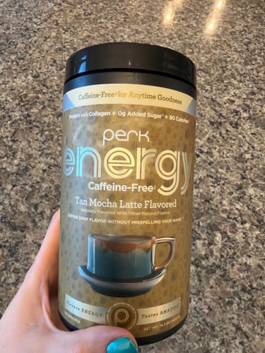 Customer holding a container of Energy CAFFEINE-FREE Tan Mocha Latte, showing the tan-colored label.