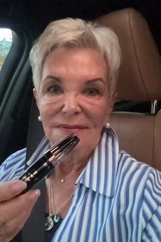 Reviewer smiling in a car while holding up the My Amazing Lashes Mascara.