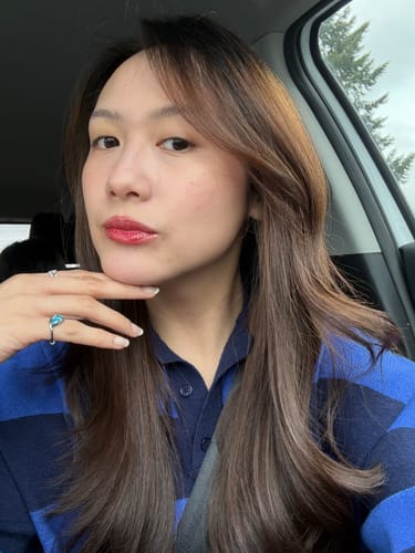 Customer wearing the Pia Birthstone Ring with a blue stone on her pinky finger in a selfie.
