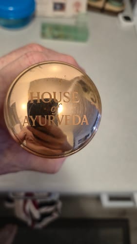 Close-up: Customer showing the engraved logo on the shiny copper lid of the water bottle.