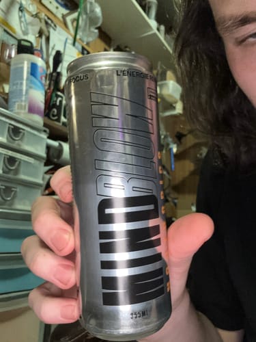 Un client tient une canette argentée de la boisson énergisante MindBlow Lite.