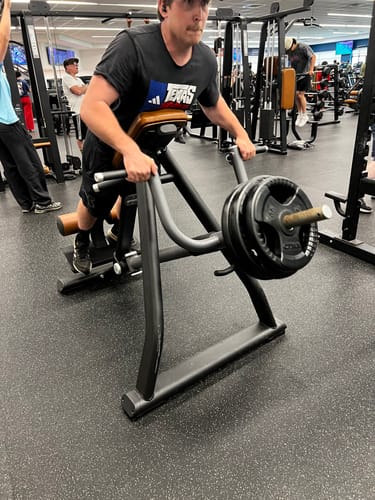 Reviewer works out on a weighted machine in the gym, in a product review for SuperCharged Honey.